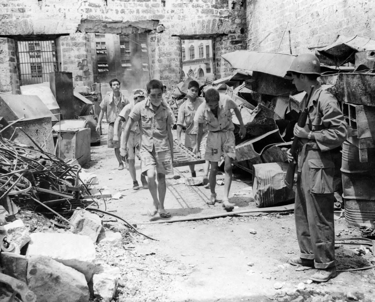 Japanese prisoners of war are supervised by American military personnel, assisting in Manila's cleanup after the battle, 1945.
