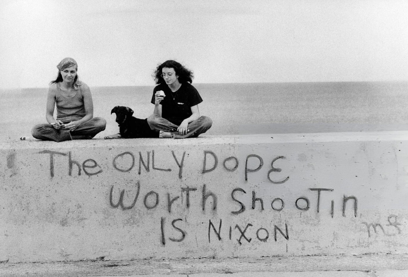 Women sit on a wall with graffiti in Winthrop, Massachusetts, 1972.
