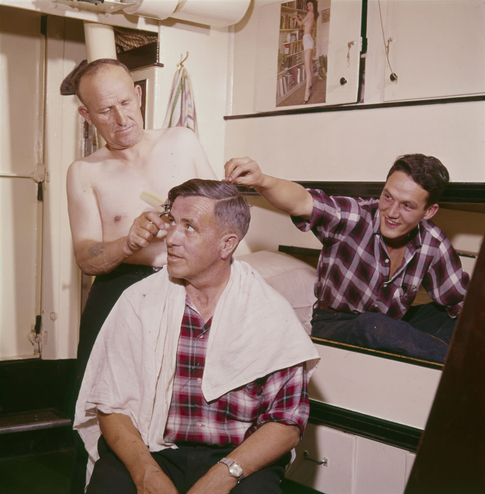 Captain Peter Troake cuts mate Ches Pelley’s hair while Gerald Drover jokes around on board the MV Christmas Seal, Newfoundland and Labrador