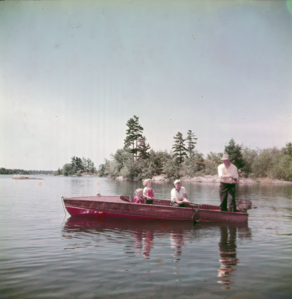 Father, mother and two little girls fly-fish in a boat on Story Lake, Ontario, 1951