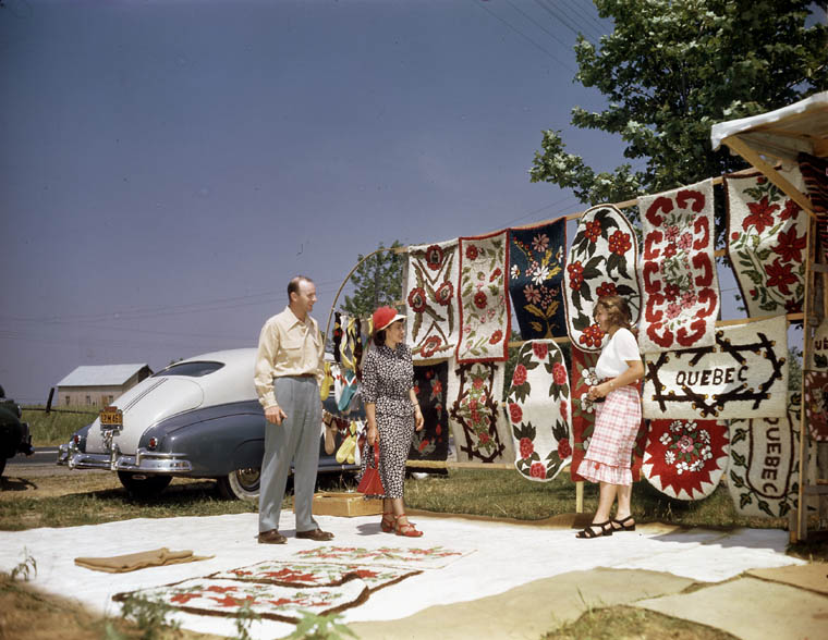 Visitors examine hooked rugs, Québec, Quebec