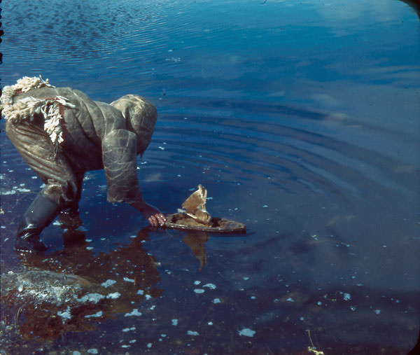 Inuit child sailing his toy boat with caribou skin sails