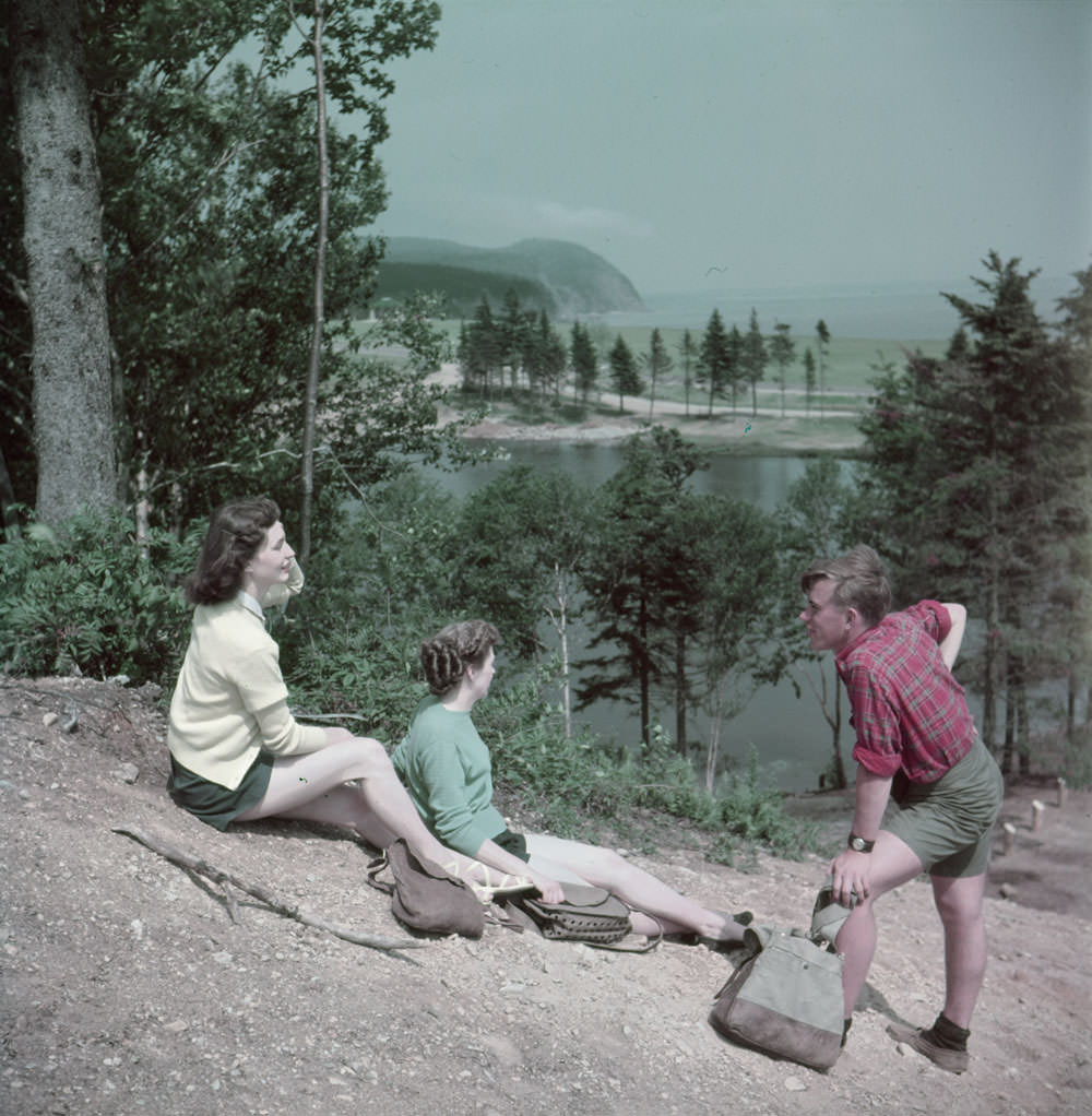 A man and two women rest on a hill above MacLaren Pond while hiking in Fundy National Park, New Brunswick ,1950
