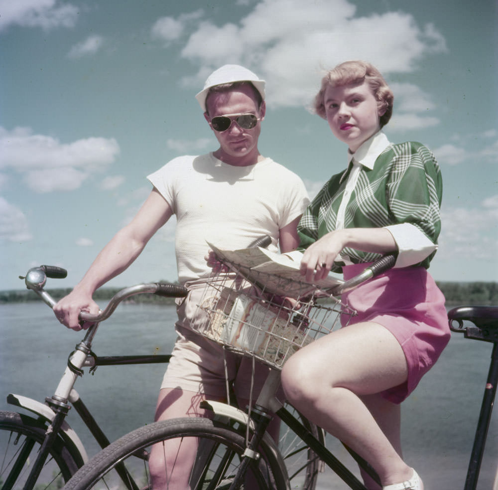 A man and a woman on bicycles consult a road map on the bank of the Ottawa River, Rockcliffe Park, Ontario, June 1952