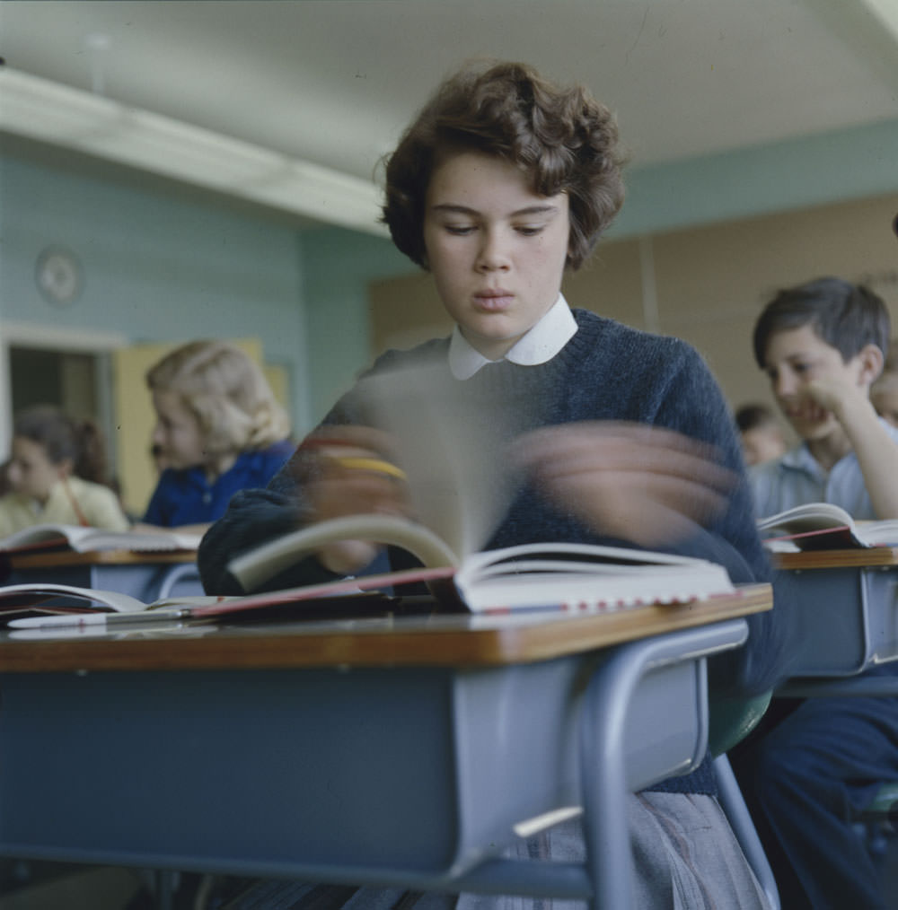 Girl sitting at desk flipping through textbook pages at Putnam School