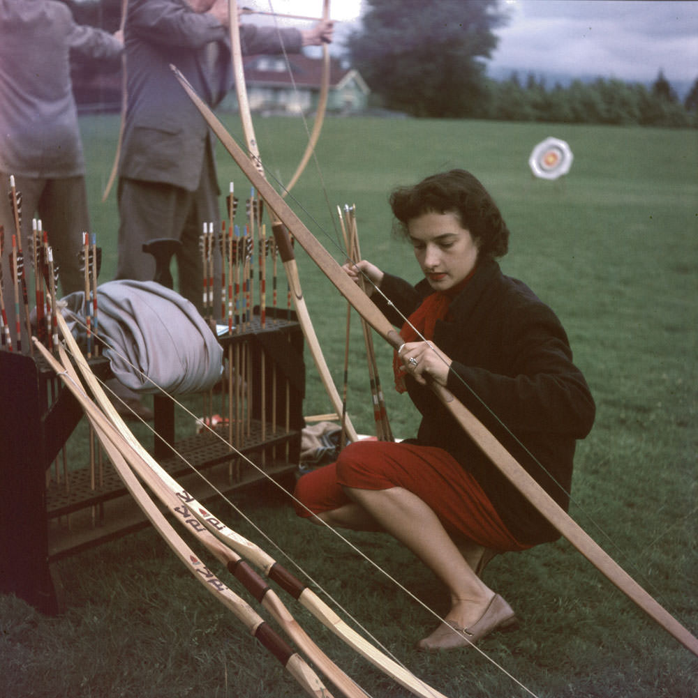 Woman kneeling with bow and arrow in her hands. Archery in Stanley Park, 1954