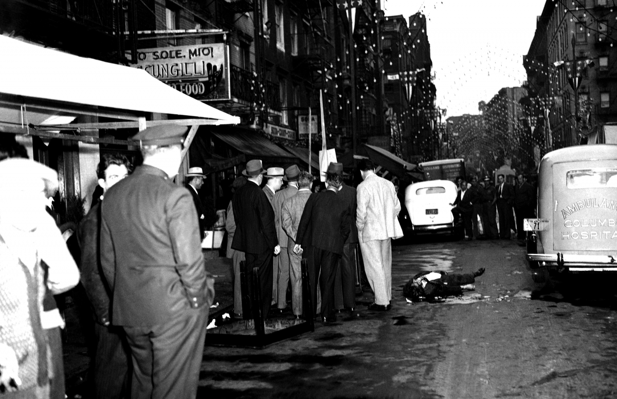 A crowd gathers around the body of a man killed in a fracas, 1939.