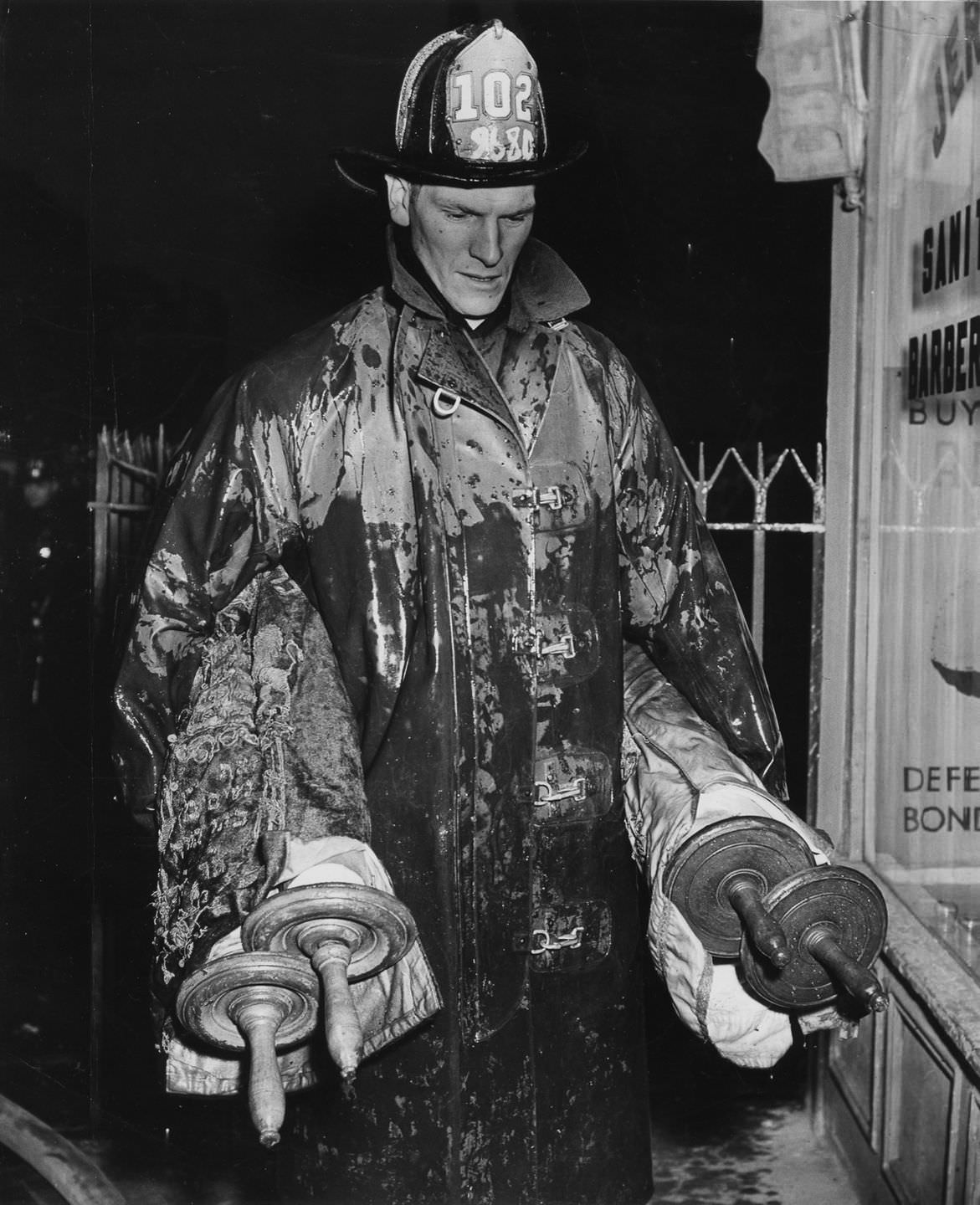 A fireman holding Torahs saved from a fire, 1943.