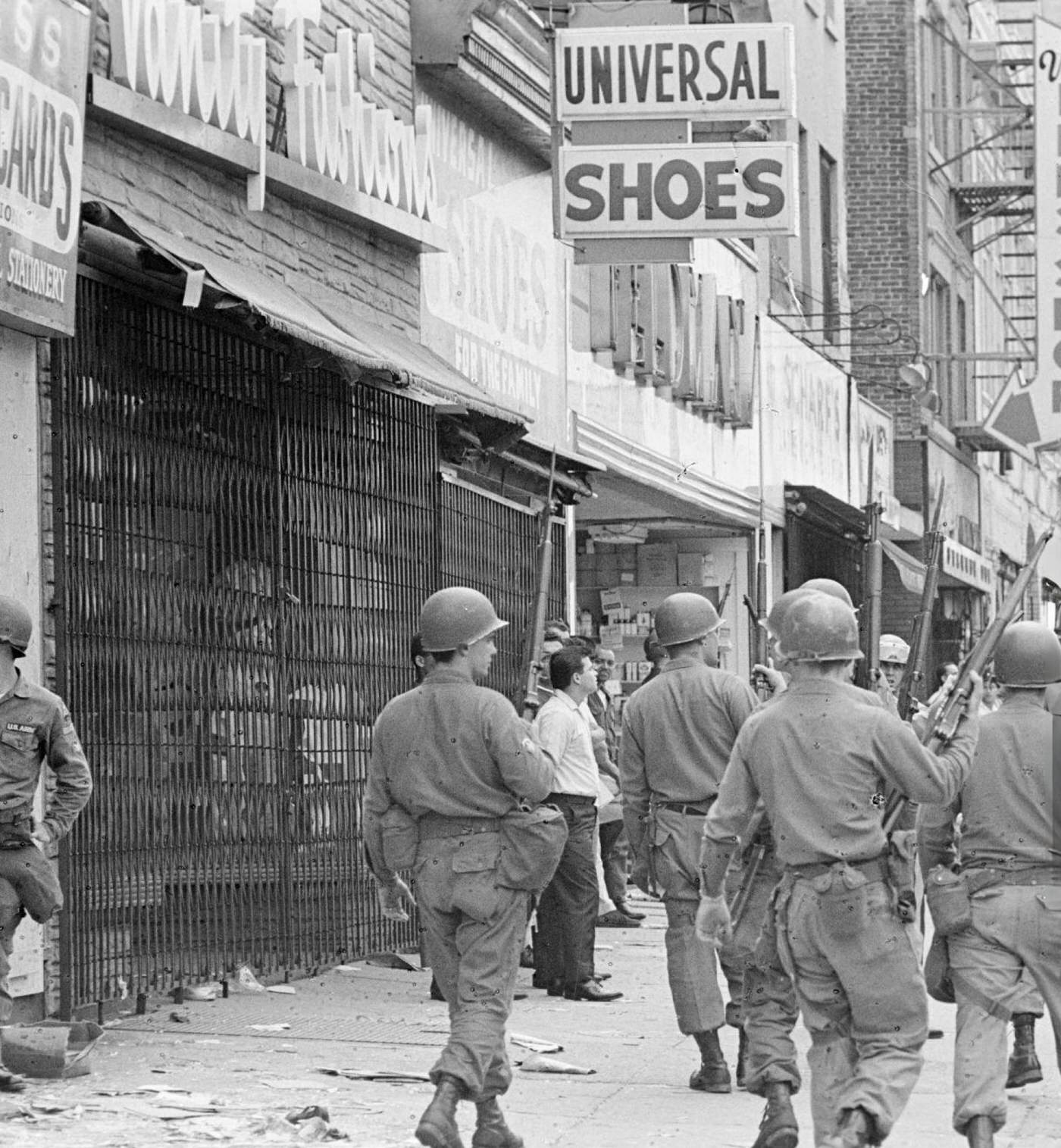 A troop of armed National Guard soldiers on patrol on a sidewalk of Springfield Avenue