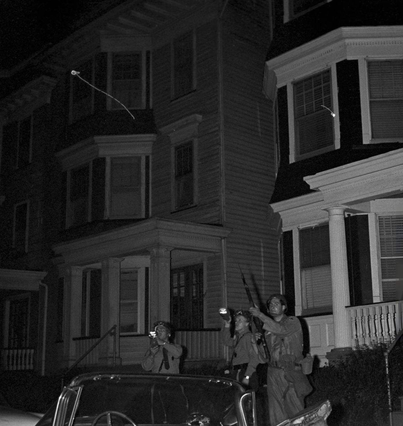 National Guard soldiers in riot helmets with bayonets raised, exhibiting flashlights