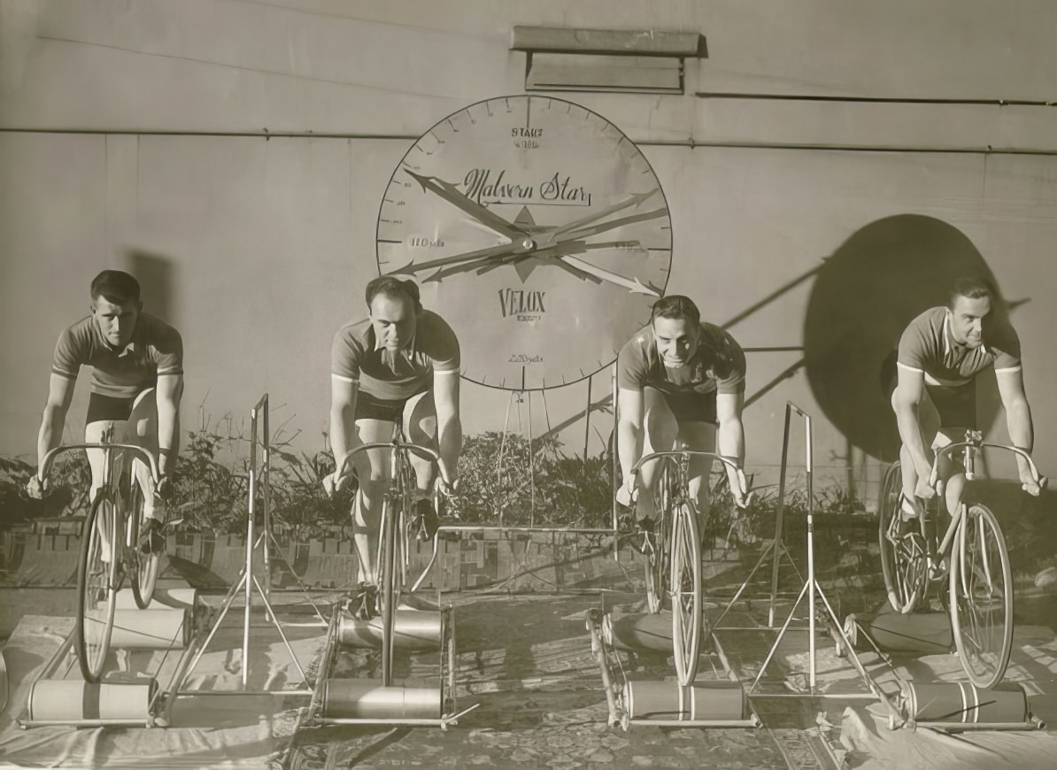 Four cyclists on speed bicycles on rollers time trials to promote Malvern Star .