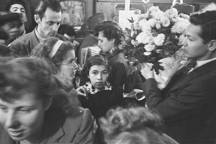 A man carrying flowers on a crowded subway, 1946.