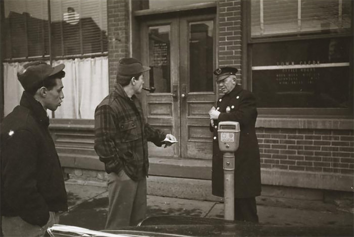 Rocky Graziano talking to a policeman on a street.