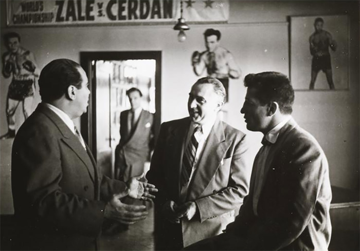 Rocky Graziano with two men by a sign for the Middleweight Championship fight between Tony Zale and Marcel Cerdan.