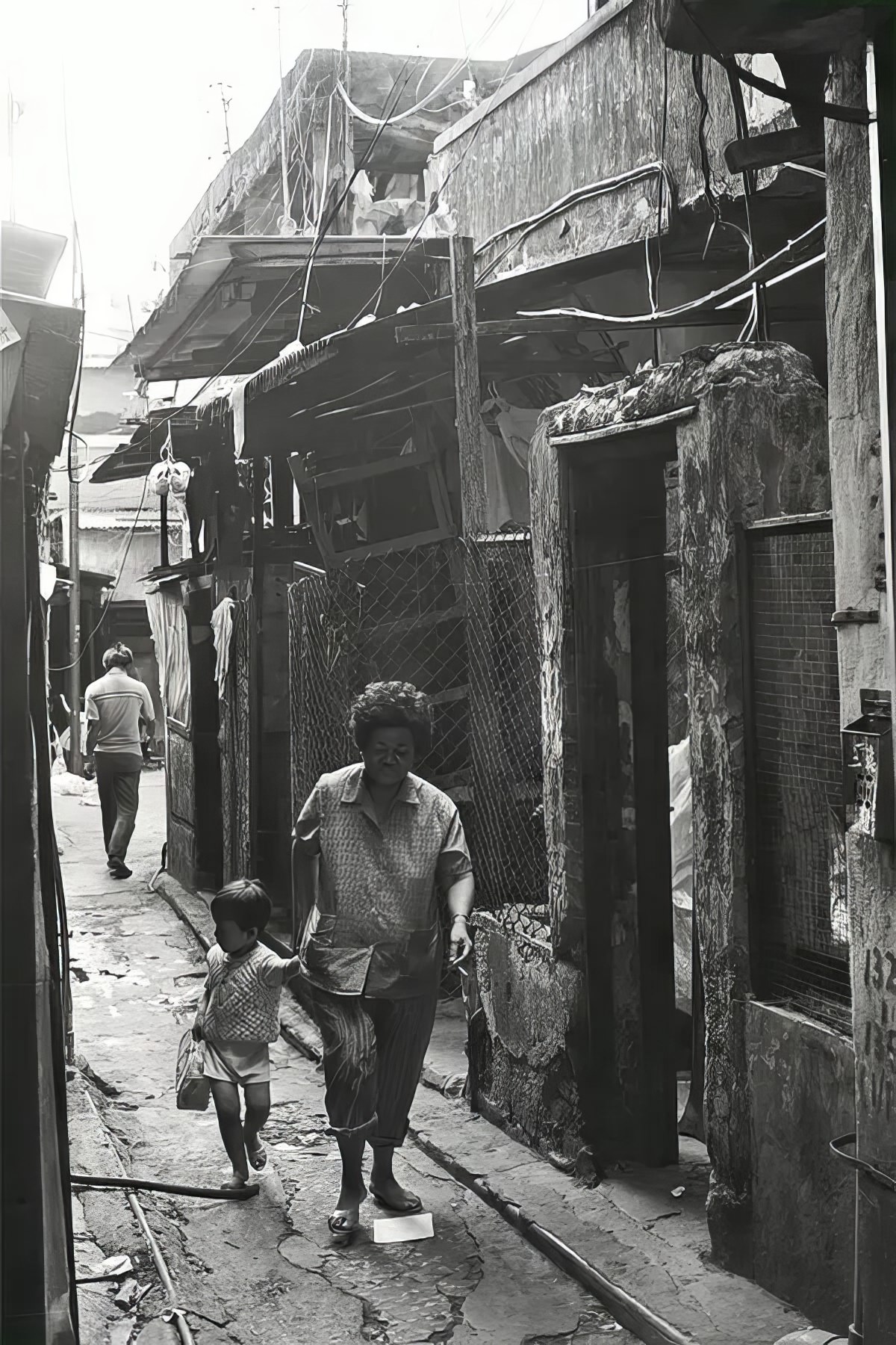 A woman and a girl make their way through Kowloon Walled City.