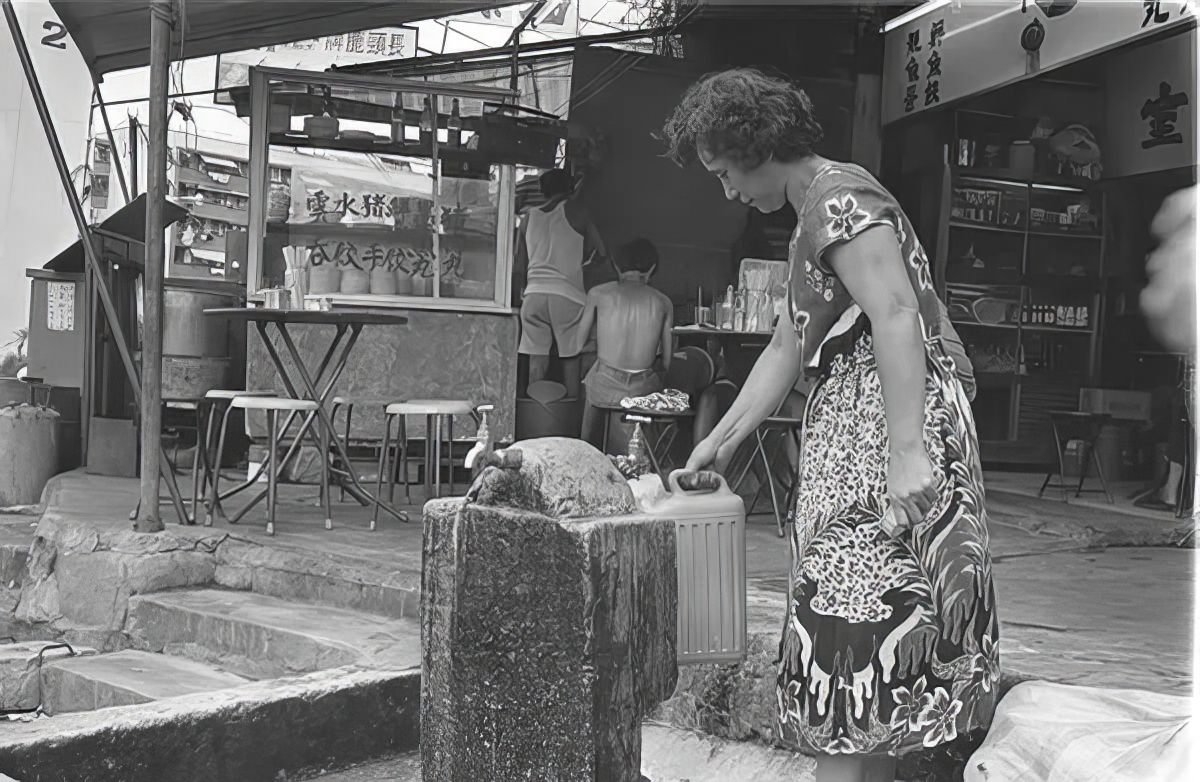 A woman gathering water in Kowloon Walled City.