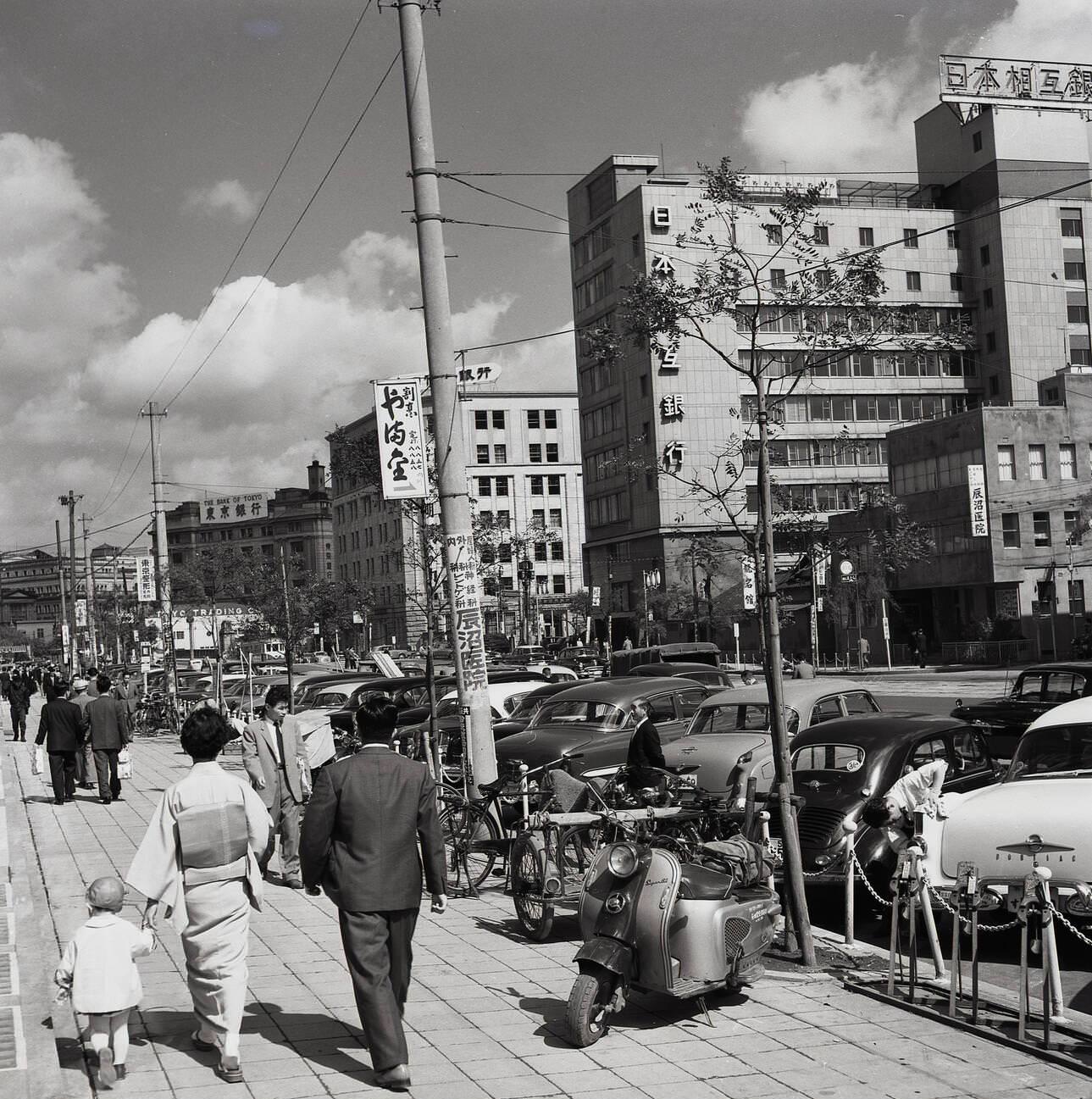 A suited man walking with a lady wearing traditional Japanese costume, 1960s.