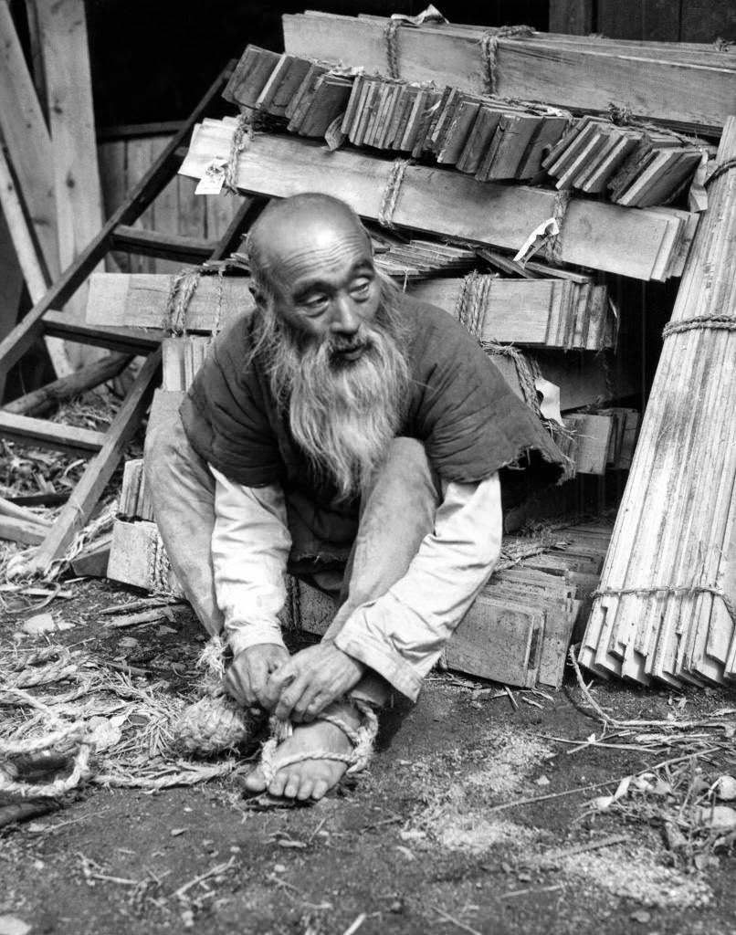 Hikosaku Sakamoto, a 63-year-old Japanese farmer, who doubles as a long distance runner and weight-lifter once each year to advertise the shrine festival in his hometown, Shirakawa, Japan, removes his straw sandals after running 125 miles from Shirakawa to Tokyo, 1946.