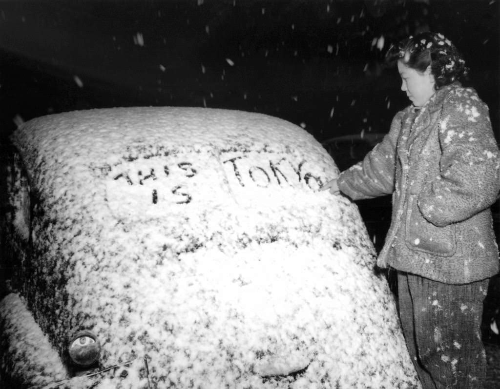 Usheeko Sato, a resident of Tokyo, Japan writes on the snow-covered rear window of an automobile, 1946.