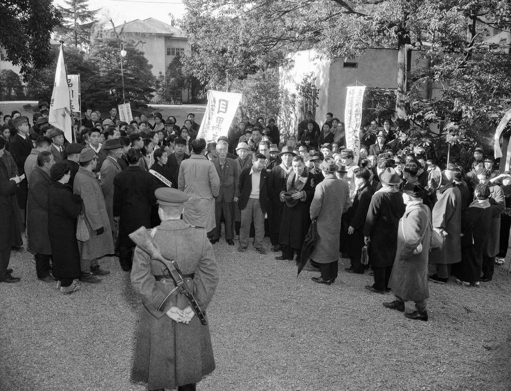 Russian soldier with tommy gun stands guard outside the Russian Embassy as the members of the “Repatriation Association of Japan” await an answer to present their case to this head of the mission in person, in Tokyo, 1949.