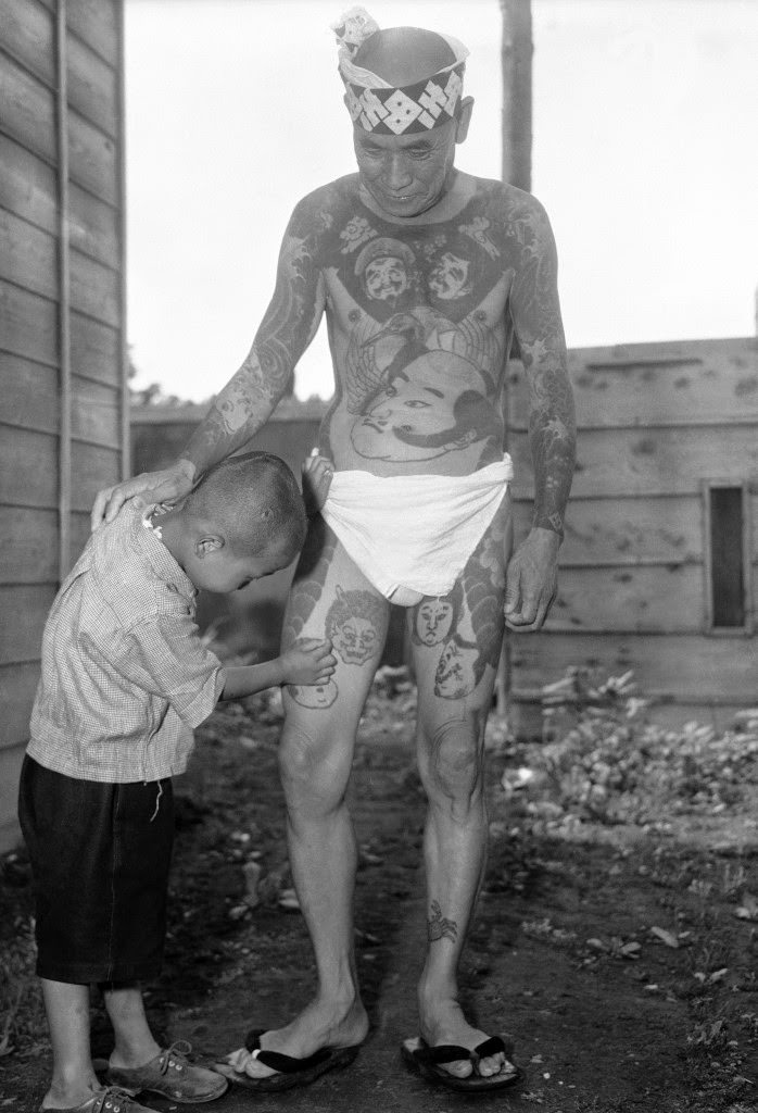 At the “Hard Skin Club” convention of tattooed men and women in Tokyo, a little boy examines a design on his father’s leg, 1948.