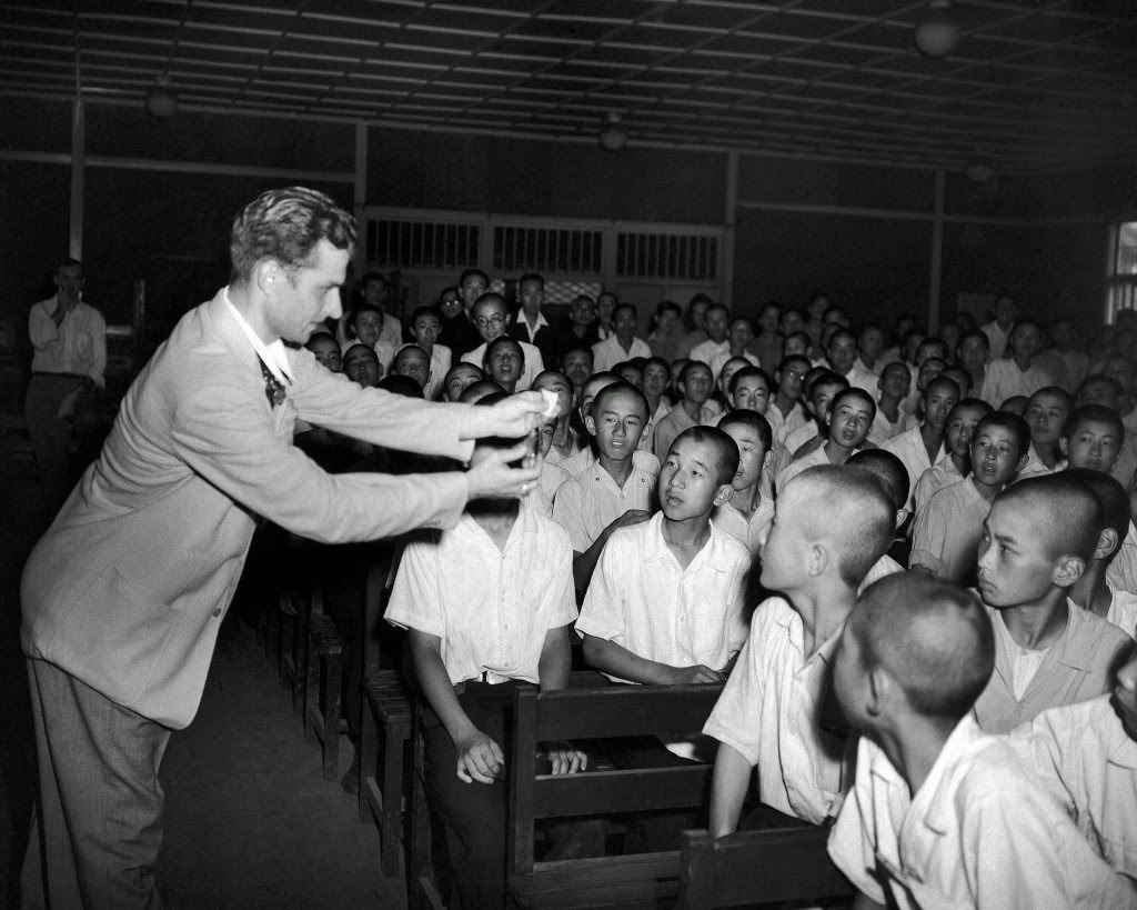 Students at the Peers'’ School in Tokyo are mystified as Jacob Tropp of Brooklyn, New York, amateur magician, makes a 50 cent piece, wrapped in tissue paper, disappear in a burst of flame, 1948.