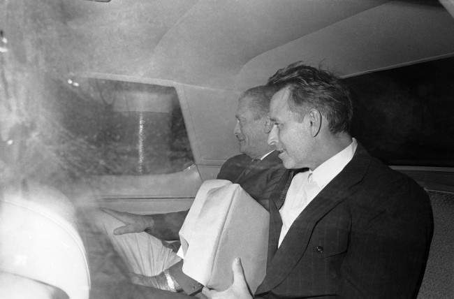 James Earl Ray, right, almost smiles as he gazes at newsmen outside the car taking him from federal court in Memphis, Tennessee, 1974.