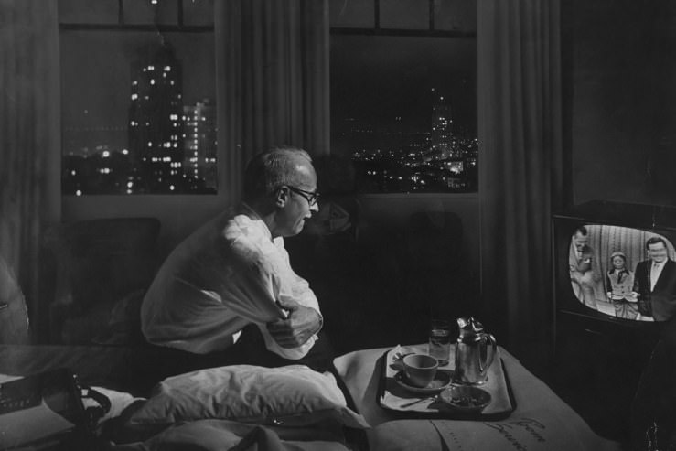 A traveling businessman watches TV in a hotel room in 1958