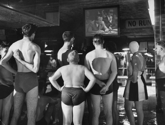 A group of swimmers at an indoor pool watch the Russian ambassador to the United Nations, Jacob Malik, filibustering in the UN Security Council in 1950