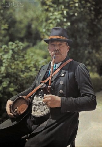 A man from Gnigl sitting with a liquor keg and pipe, Austria, 1930.