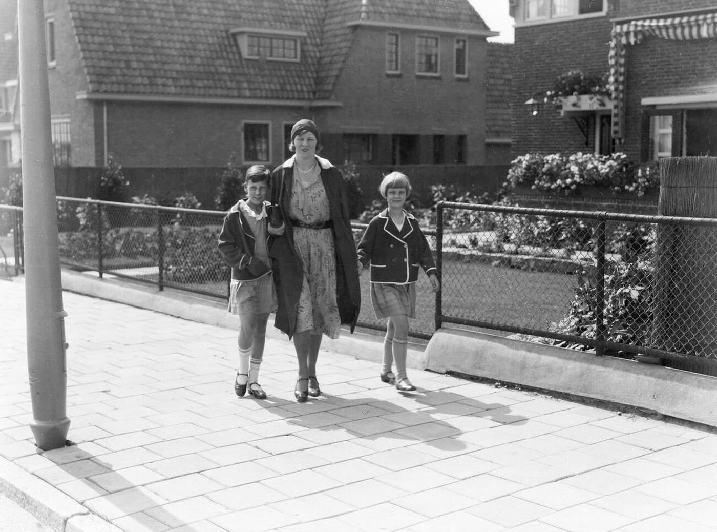 Mother with daughters walking on a sidewalk in Amsterdam, 1930s.