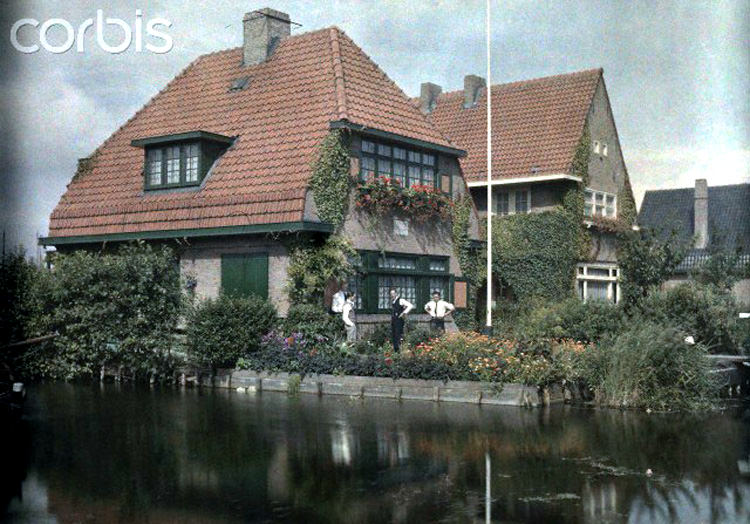 Men converse in the garden of their home on the canal in Aalsmeer, 1930s.
