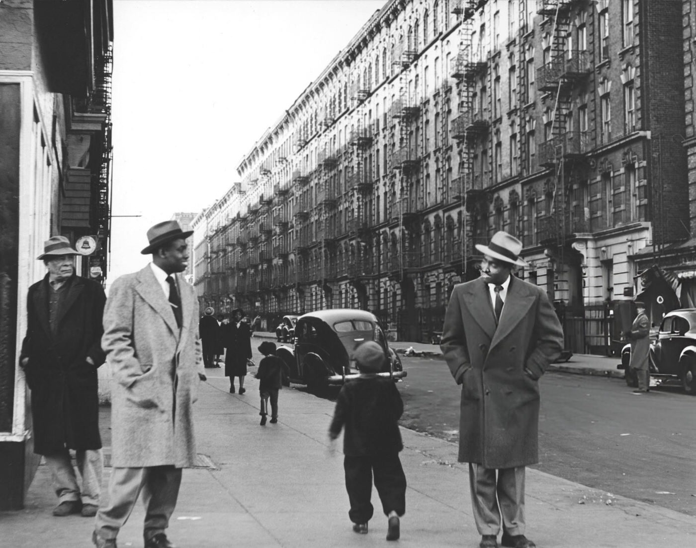 Two unidentified men greet each other on a Haarlem sidewalk, New York, 1930s.