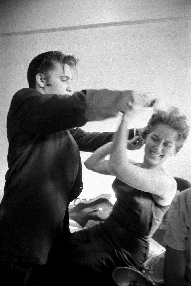 Backstage at the Mosque Theatre, Richmond, Virginia, Elvis messing with Bobbi Owen's hair, 1956.