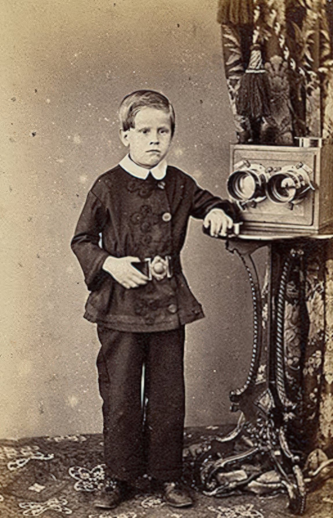 This European carte-de-visite is by W. Freudentheil. It seems unlikely that the grim faced little boy in the strange coat could manage the large stereo camera beside him.