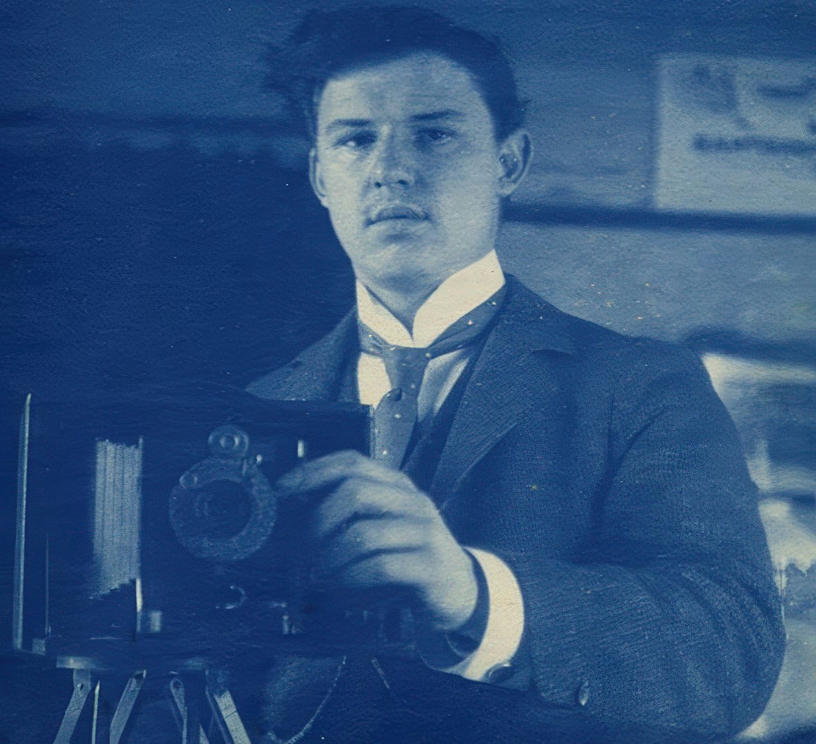 A cyanotype self portrait with a folding camera taken in a mirror.