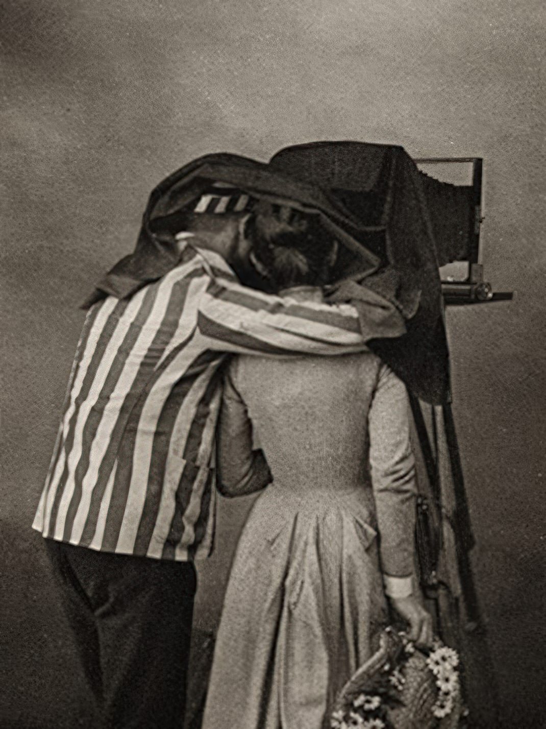 This image called "Focusing" by Miss Emily V. Clarkson was printed by the NN Photogravure. company Since we are a couple absorbed in all things photographic we find this couple sharing a darkcloth especially poignant. Why, however, is he wearing that striped coat and cap?