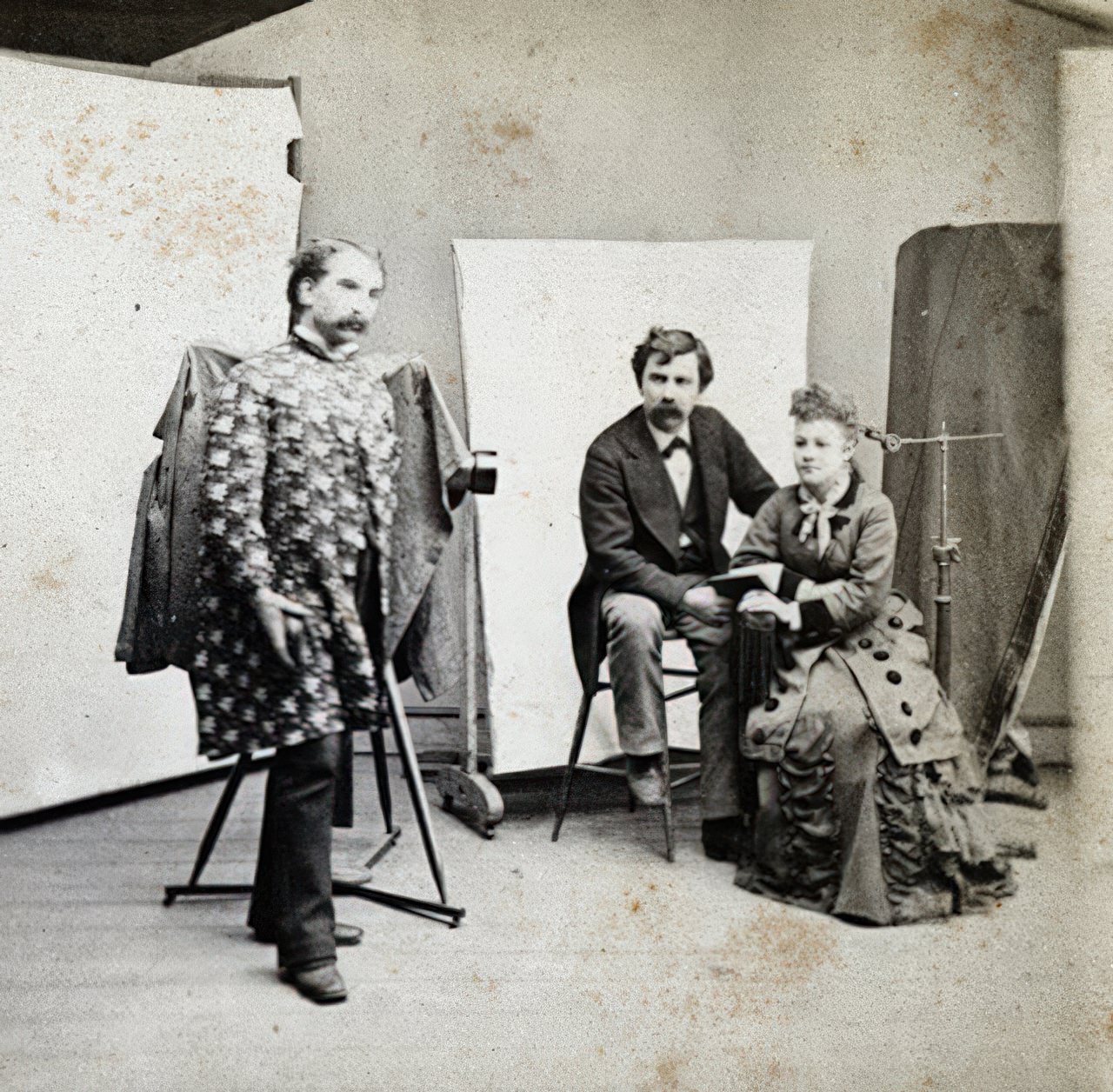 This is half of a stereo card that is marked "E. M. Johnson, Photographer, Crown Point, N.Y.". Mr. Johnson wears a rather bazarre printed coat while he photographs a couple.