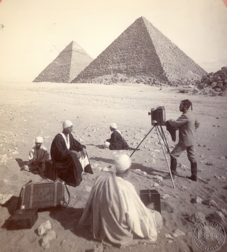 This stereo card, with an 1882 copyright, shows the photographic party of Edward L. Wilson in Egypt.. The title of the card is "Photographing Cephren and Mencheres" from the series "Scenes in the Orient".
