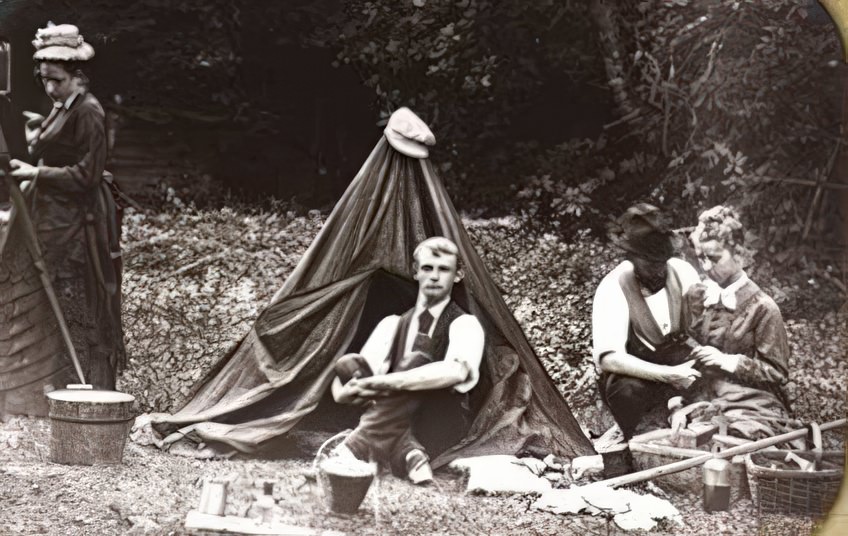 This is a collodion negative that has been mounted as a lantern slide. It has been labeled by the photographer "Wet col neg Wet col positive". The paper mat tells us it was made in 1873 in Belvidere, New Jersey. It names the young men (it appears that the young women did not rate naming) are H. W. Hazard and John C. Browne. The camera peeks out of the mat on the left side but the dark tent, buckets, and other supplies give us a delightful window on what was involved in an afternoon of photographing in 1873.
