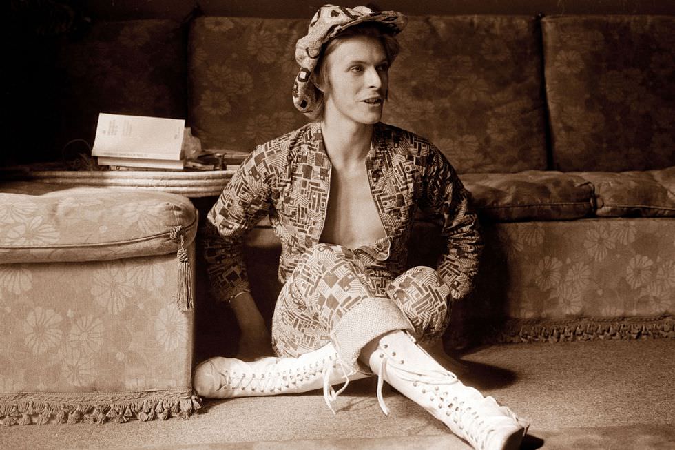 David Bowie in lace-up boots and a printed jumpsuit being interviewed at home in Beckenham, London, 1972.