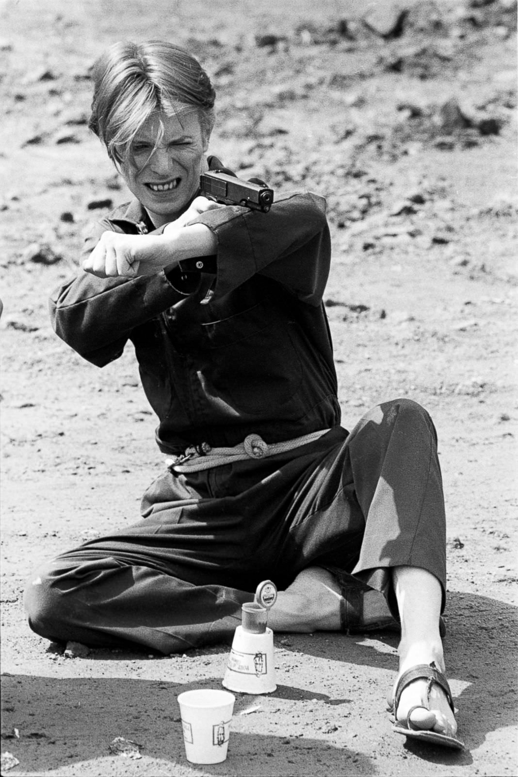 David Bowie target practicing on the set of The Man Who Fell to Earth, New Mexico, 1975.