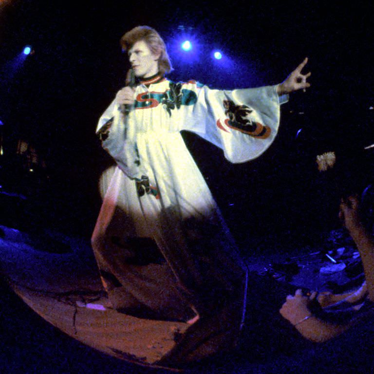 David Bowie in a billowing robe performing onstage, 1973.