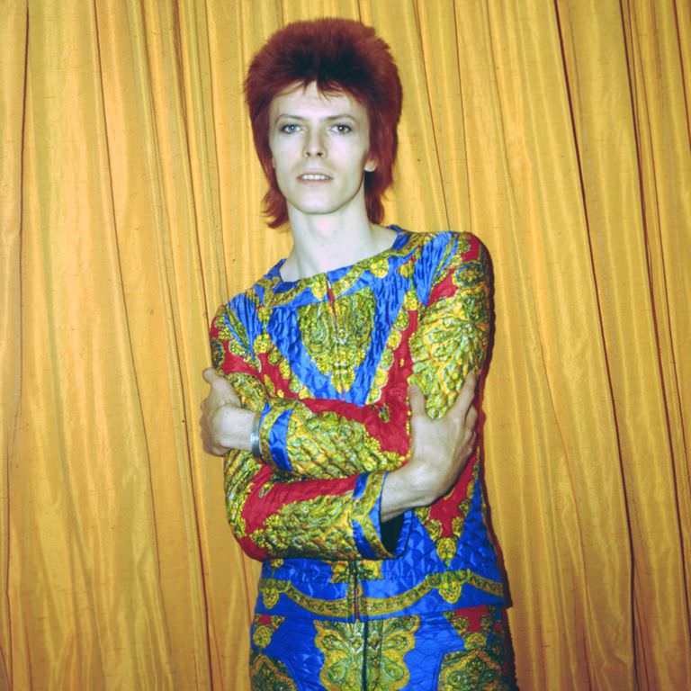 David Bowie in a colorful quilted outfit photographed in a New York City hotel room, 1973.