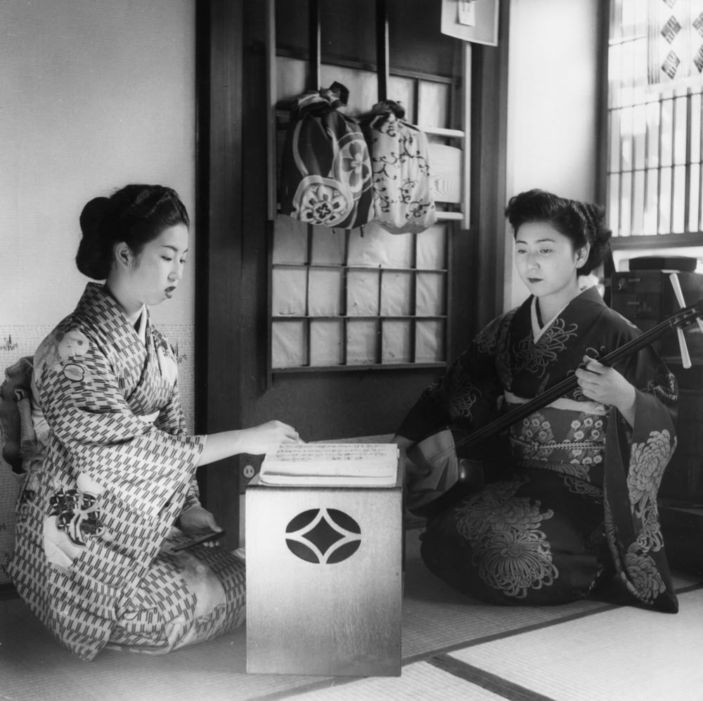Geisha girls practicing their art; one plays a samisen, 1950s.