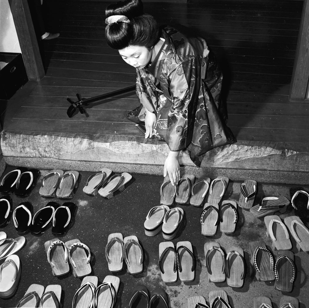 A Geisha girl arranging her footwear, 1950s.