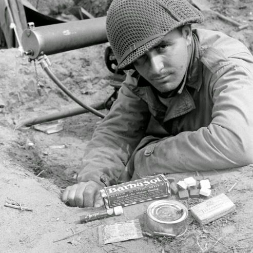 William P. Chirolas displays supplies disliked by M Company soldiers at Anzio, 1944.