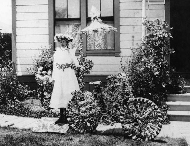 Leela McAdam (McCabe), winner of the best decorated bicycle for the 1900 Fourth of July parade in Lompoc, stands outside her home at 137 S. J. Street. Her bicycle, her belt, and her hat were decorated with sweet peas.