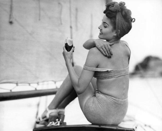 Circa 1950s: Woman applying suntan lotion.