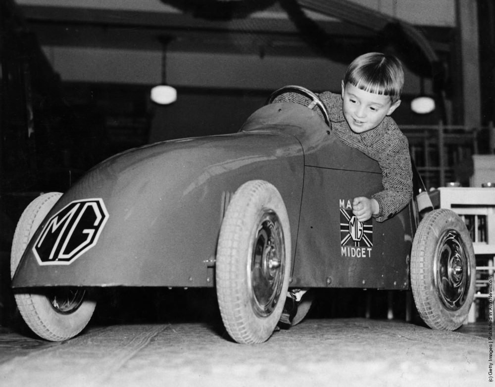 A young boy trying out a toy MG Midget car at the famous toy shop Hamleys, on Regent Street, London. 18th November 1934.